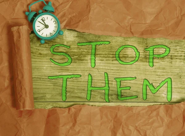 Escribiendo una nota que muestra Stop Them. Exhibición de fotos de negocios utilizada para decirle a alguien que no haga algo que está haciendo Reloj despertador y cartón roto en un fondo de mesa clásico de madera . —  Fotos de Stock