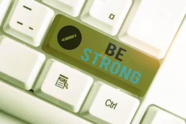 Kavramsal el yazısı Güçlü Olun 'u gösteriyor. İş fotoğrafı gösterimi, hayattaki büyük koşullara ya da baskıya dayanabilir beyaz arka planda nota kağıdıyla birlikte beyaz pc klavye.