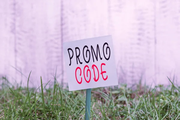 Tekstbord met Promo Code. Conceptuele foto digitale nummers die geven u goede korting op bepaalde product Plain leeg papier bevestigd aan een stok en geplaatst in het groene grasland. — Stockfoto