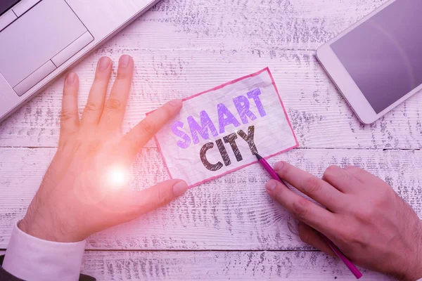 Psaný text Smart City. Obchodní koncept pro městské oblasti, která používá různé elektronické Internet věcí Ruční držet poznámkový papír v blízkosti psaní zařízení a moderní smartphone zařízení. — Stock fotografie