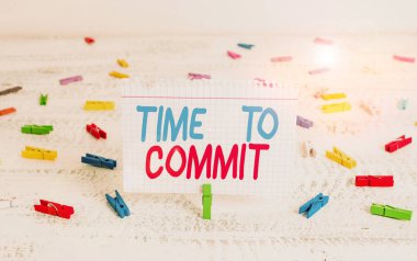 Handwriting text writing Time To Commit. Concept meaning Engagement or obligation that restricts freedom of action Green clothespin white wood background colored paper reminder office supply. clipart