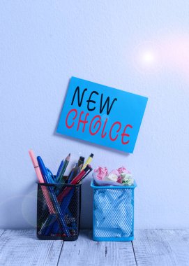 Text sign showing New Choice. Conceptual photo having lot of options and adding another one to choose between Blue Sticky Card on Wall Two Pencil Pots Pens Pencils Markers Waste Paper.