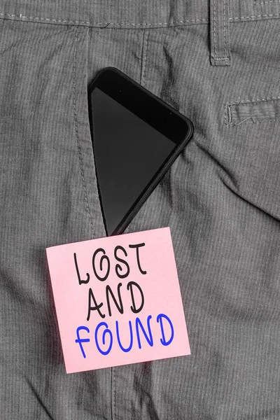 Handwriting text Lost And Found. Concept meaning Place where you can find forgotten things Search service Smartphone device inside formal work trousers front pocket near note paper.