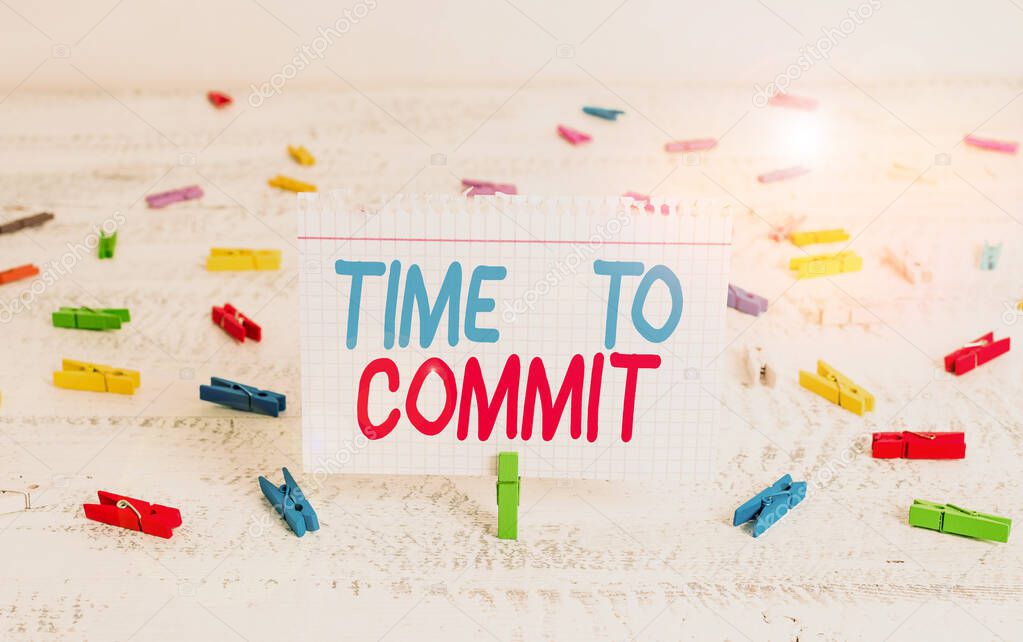 Handwriting text writing Time To Commit. Concept meaning Engagement or obligation that restricts freedom of action Green clothespin white wood background colored paper reminder office supply.