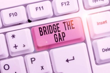 Bridge The Gap 'i gösteren bir not yazıyorum. İş fotoğrafı gösterimi engelleri aşar Cesaret Güçlendirme Klavyesi beyaz arkaplan anahtar alanı üzerine not kağıdı ile.