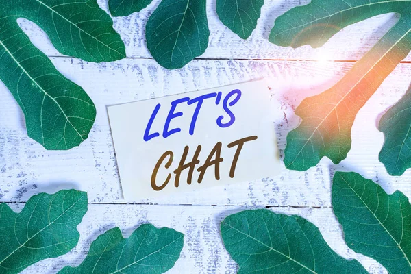 Writing note showing Let S Is Chat. Business photo showcasing inviting the demonstrating to have informal conversation with you Leaves surrounding notepaper above a classic wooden table.