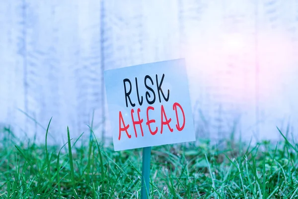 Text sign showing Risk Ahead. Conceptual photo A probability or threat of damage, injury liability and loss Plain empty paper attached to a stick and placed in the green grassy land. — Stock Photo, Image