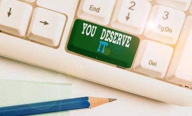 Text sign showing You Deserve It. Conceptual photo Reward for something well done Deserve Recognition award White pc keyboard with empty note paper above white background key copy space.