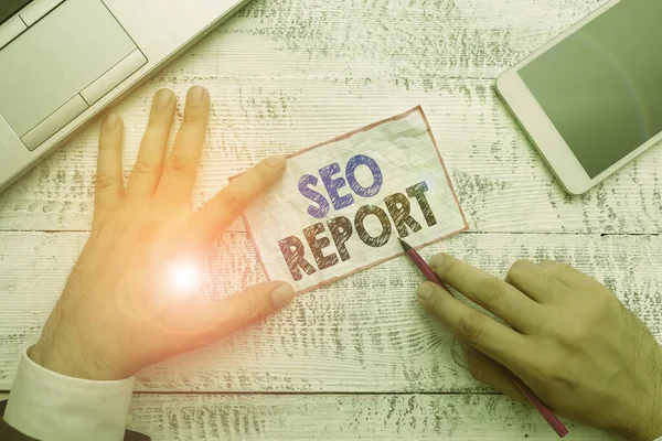 Ordskrivning text Seo Report. Affärsidé för att meddela om hur webbplatsen fungerar i sökmotorresultat Hand hålla anteckning papper nära skrivutrustning och modern smartphone-enhet. — Stockfoto