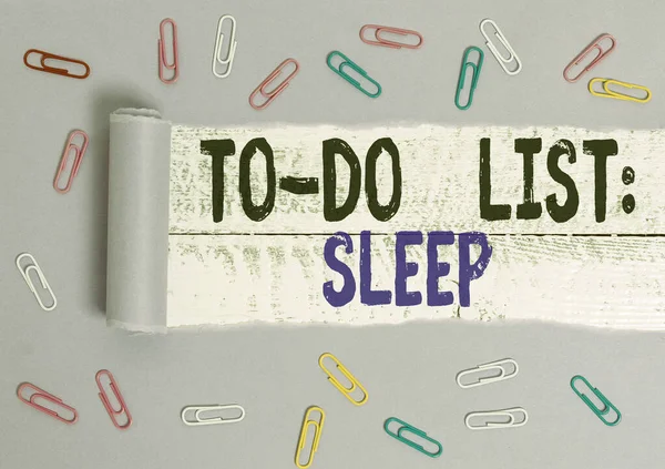 Handwriting text To Do List Sleep. Concept meaning Things to be done Priority object is to take a rest Paper clip and torn cardboard placed above a wooden classic table backdrop.