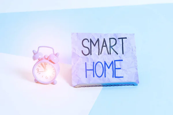 Handwriting text writing Smart Home. Concept meaning automation system control lighting climate entertainment systems Mini size alarm clock beside a Paper sheet placed tilted on pastel backdrop. — Stockfoto
