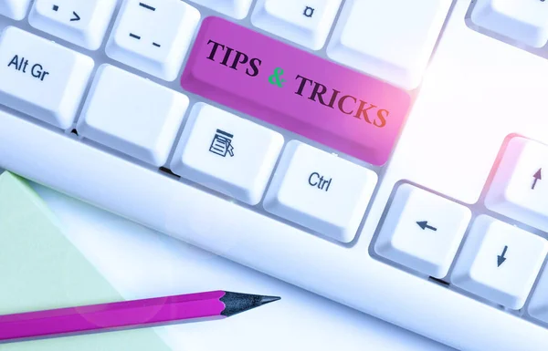 Writing note showing Tips And Tricks. Business photo showcasing Steps Lifehacks Handy advice Recommendations Skills White pc keyboard with note paper above the white background.
