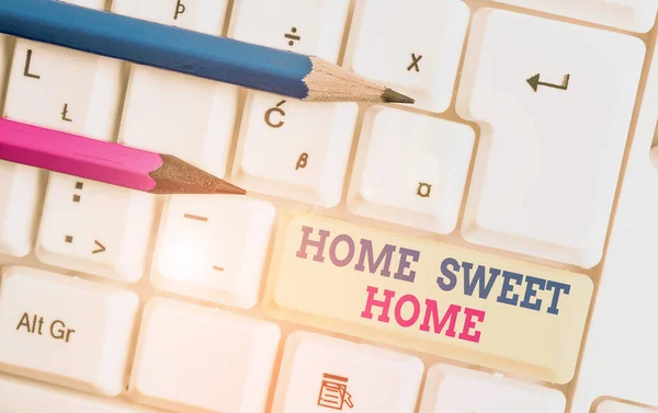 Schrijfbriefje met Home Sweet Home. Zakelijke foto showcasing In huis eindelijk Comfortabel gevoel Ontspannen Familie tijd Witte pc toetsenbord met nota papier boven de witte achtergrond. — Stockfoto