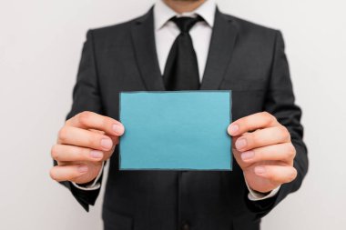 Erkek insan duruşu ve resmi iş kıyafetleri giymek eski not kağıtlarını tutar. İş elbisesi ve kravat ofisi giymiş bir adam elinde küçük bir not kağıdı tutuyor.