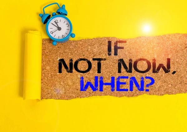 Handwriting text writing If Not Now When Question. Concept meaning start acting from this moment do not hesitate Alarm clock and torn cardboard placed above a wooden classic table backdrop.