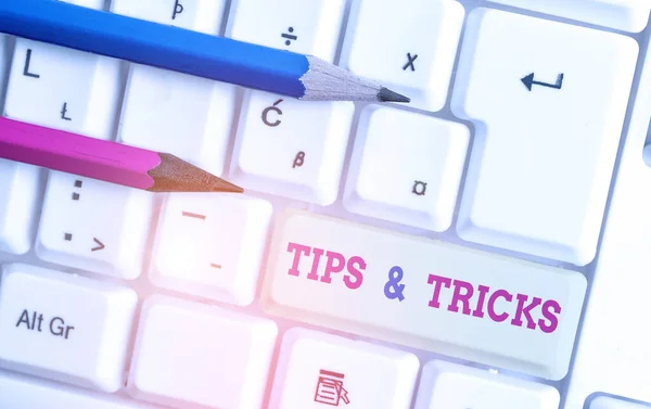 Writing note showing Tips And Tricks. Business photo showcasing Steps Lifehacks Handy advice Recommendations Skills White pc keyboard with note paper above the white background.