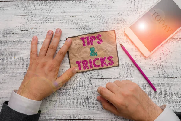 Text sign showing Tips And Tricks. Conceptual photo Steps Lifehacks Handy advice Recommendations Skills Hand hold note paper near writing equipment and modern smartphone device. — Stock Photo, Image