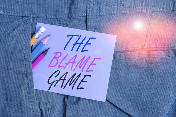 Writing note showing The Blame Game. Business photo showcasing A situation when showing attempt to blame one another Writing equipment and purple note paper inside pocket of trousers. — Stockfoto