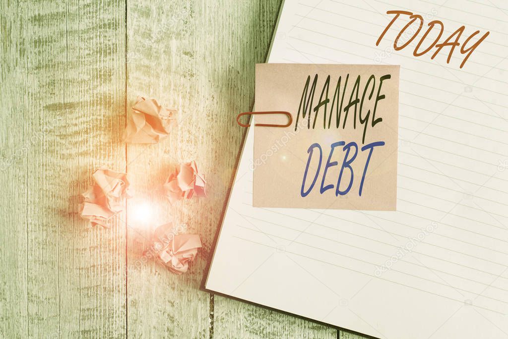 Writing note showing Manage Debt. Business photo showcasing unofficial agreement with unsecured creditors for repayment Notebook stationary placed above classic wooden backdrop.