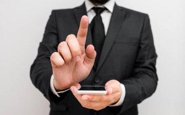 Sakallı bir erkek resmi iş kıyafetleri giyer yüksek teknoloji akıllı telefon cihazı taşır. İş elbisesi giymiş bir adam ve kravatlı küçük cep telefonlu bir adam tek elini kullanıyor.