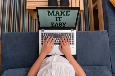 Make It Easy 'i gösteren bir not yazıyorum. İş fotoğraflarının gösterdiği akıllı yaklaşım endişe ve zorluklardan uzak kadın dizüstü bilgisayar bürosu içerideki teknolojik cihazları sağlıyor..
