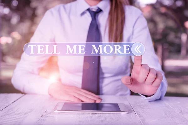 Handwriting text Tell Me More. Concept meaning A call to start a conversation Sharing more knowledge Female business person sitting by table and holding mobile phone. — Stock Photo, Image