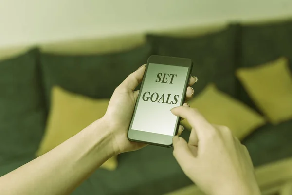 Word writing text Set Goals. Business concept for Defining or achieving something in the future based on plan woman using smartphone office supplies technological devices inside home.