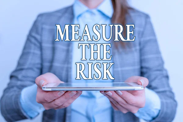 Handwriting text writing Measure The Risk. Concept meaning determine degree of danger based on impact factors Business concept with mobile phone and business woman.