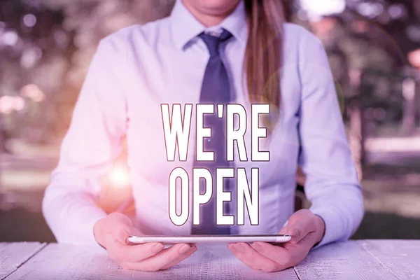 Writing note showing We Re Open. Business photo showcasing answering on client that shop is available at this time Female business person sitting by table and holding mobile phone. — Stock Photo, Image
