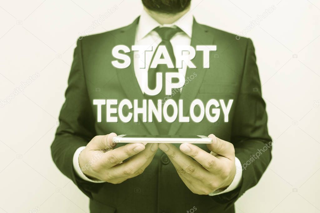 Text sign showing Start Up Technology. Conceptual photo Young Technical Company initially Funded or Financed Male human wear formal work suit hold smart hi tech smartphone use hands.