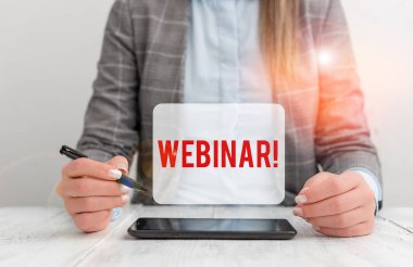 Text sign showing Webinar. Conceptual photo a seminar or other presentation that takes place on the Internet Business woman sitting with mobile phone and pen in the hand.