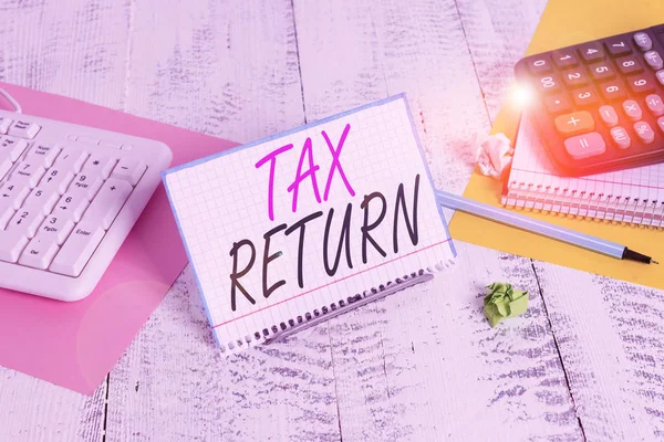 Text sign showing Tax Return. Conceptual photo Tax payer financial information Tax Liability and Payment report Notepaper stand on buffer wire in between computer keyboard and math sheets. — Stock Photo, Image