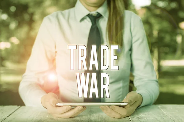 Writing note showing Trade War. Business photo showcasing a situation in which countries try to damage each other s is trade Female business person sitting by table and holding mobile phone.