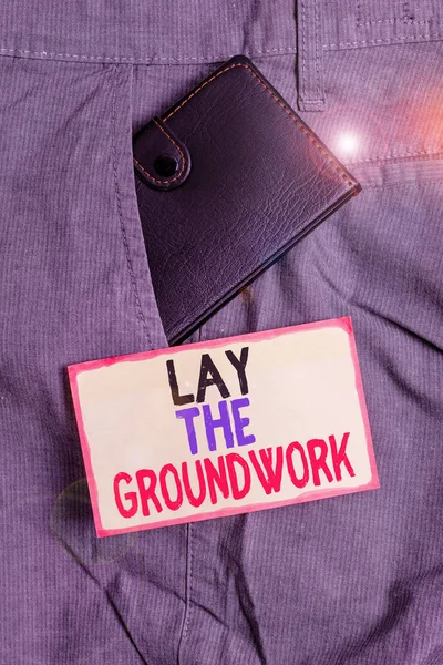 Conceptual hand writing showing Lay The Groundwork. Business photo showcasing Preparing the Basics or Foundation for something Small wallet inside trouser front pocket near notation paper.