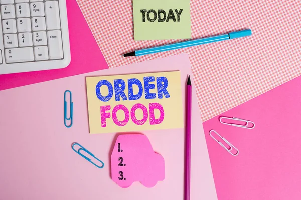 Writing note showing Order Food. Business photo showcasing the process of requesting a preferred food in a restaurant Writing equipments and computer stuffs placed above colored plain table.