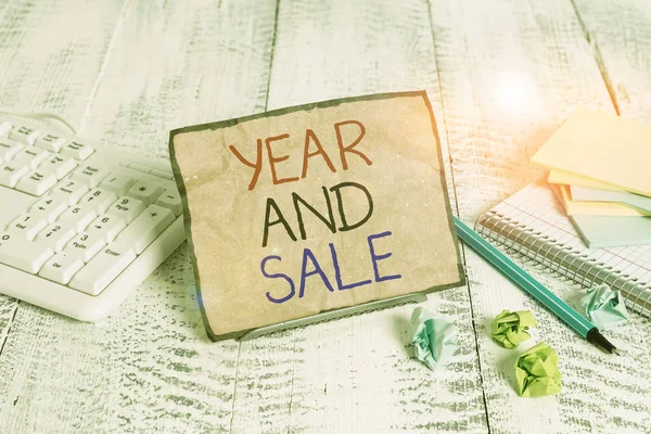 Conceptual hand writing showing Year And Sale. Business photo showcasing Annual Discounts Holiday Season clearance Traditional Notepaper on wire in between computer keyboard and sheets. — Stock Photo, Image