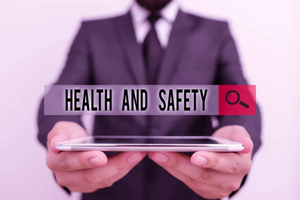 Text sign showing Health And Safety question. Conceptual photo regulations and procedures to prevent accident Male human wear formal work suit hold smart hi tech smartphone use hands. — 图库照片