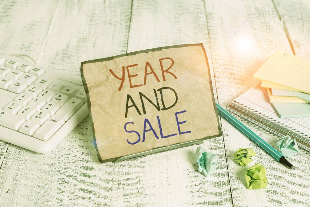 Conceptual hand writing showing Year And Sale. Business photo showcasing Annual Discounts Holiday Season clearance Traditional Notepaper on wire in between computer keyboard and sheets.