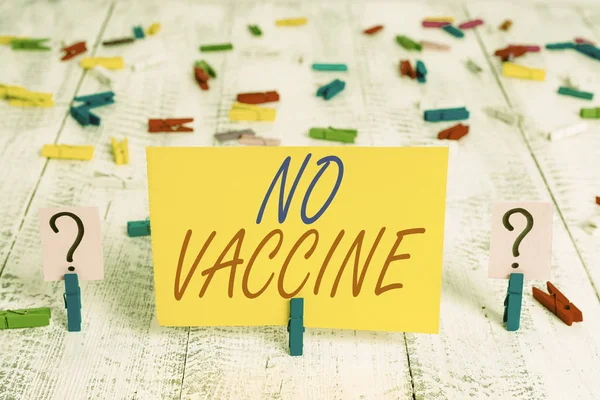 Writing note showing No Vaccine. Business photo showcasing not provided of immunity against one or several diseases Crumbling sheet with paper clips placed on the wooden table.