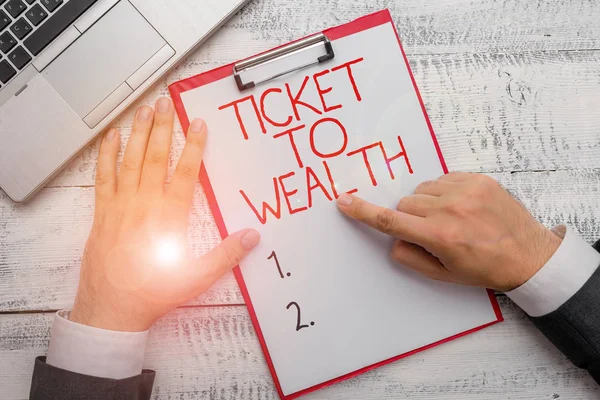 Text sign showing Ticket To Wealth. Conceptual photo Wheel of fortune Passage to Successful and brighter future Hand hold writing equipment tool near modern high technology laptop device.