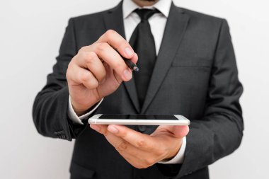 Sakallı bir erkek resmi iş kıyafetleri giyer yüksek teknoloji akıllı telefon cihazı taşır. İş elbisesi giymiş bir adam ve kravatlı küçük cep telefonlu bir adam tek elini kullanıyor.