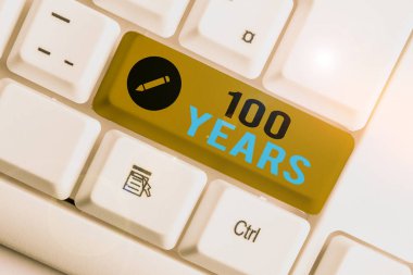 Kavramsal el yazısı 100 yılı gösteriyor. 100 yıldır var olan özel bir günü anımsıyor. Beyaz arka planda not kağıdı olan beyaz bilgisayar klavyesi..