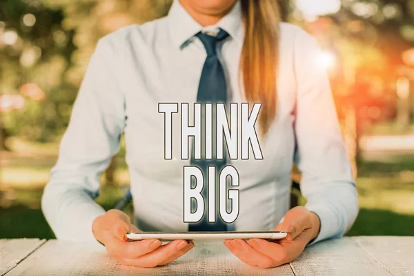 Escribiendo una nota que muestra Think Big. Exposición de fotos de negocios Para planear algo de alto valor para uno mismo o para la preparación Mujer de negocios sentada junto a la mesa y sosteniendo el teléfono móvil . — Foto de Stock