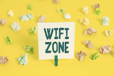 Word writing text Wifi Zone. Business concept for provide wireless highspeed Internet and network connections Colored crumpled papers empty reminder white floor background clothespin.