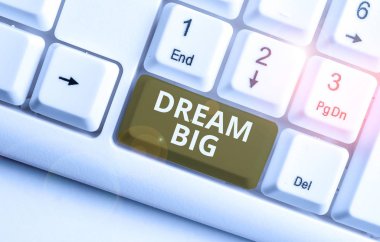Dream Big 'i gösteren bir not yazıyorum. Hayatınız için amaç arayan bir iş fotoğrafı gösterimi ve beyaz arkaplanının üzerinde nota kağıdıyla birlikte beyaz bilgisayar klavyesinde gerçekleştirilme işlemi.