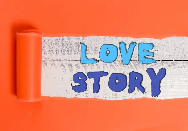 Píšu text Love Story. Obchodní koncept pro to je něco jako román nebo film o milostné aférce Karton, který je roztržen uprostřed umístěn nad dřevěným klasickým stolem. — Stock fotografie