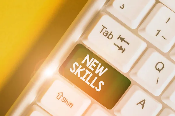 Text sign showing New Skills. Conceptual photo Recently Acquired Learned Abilities Knowledge Competences White pc keyboard with empty note paper above white background key copy space. — Stockfoto