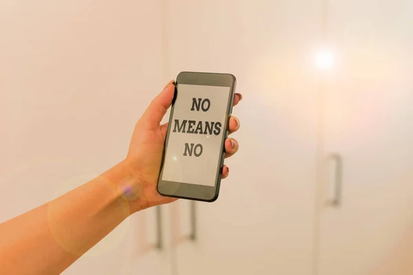 Writing note showing No Means No. Business photo showcasing Stop abuse gender violence Negative response Sexual harassment woman using smartphone and technological devices inside the home.