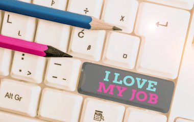 İşimi sevdiğimi gösteren kavramsal el yazısı. İş fotoğrafı gösterimi İşgal üzerine atanan günlük görevin keyfini çıkarırken Beyaz PC klavye üzerinde beyaz arkaplan üzerinde not kağıdı ile birlikte.