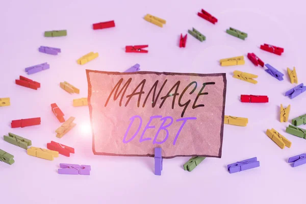Handwriting text writing Manage Debt. Concept meaning unofficial agreement with unsecured creditors for repayment Colored clothespin papers empty reminder white floor background office.